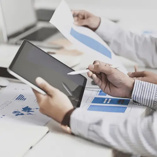 A person holding an tablet and discussing with another person over some graphs